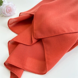 Close-up of lightweight orange linen-cotton scarf fabric with soft floral decoration