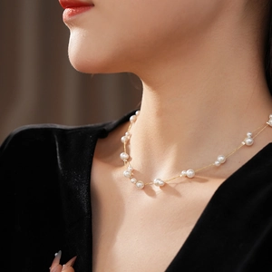 Gros plan d'un collier élégant à double chaîne dorée avec petites perles blanches sur modèle
