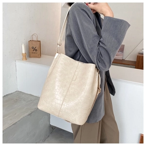 Close-up of cream crocodile pattern bucket bag with adjustable wide shoulder strap detail