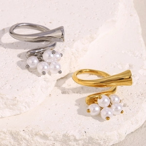 Detailed shot of irregular 18K gold and silver rings with pearls on a textured stone