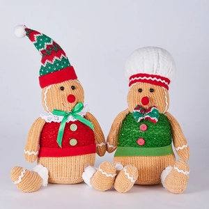 Detailed close-up of gingerbread gnome plush dolls with red and green knitted Christmas outfits
