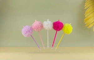 Détail de cinq stylos licorne en peluche colorés violet rose et blanc sur support clair