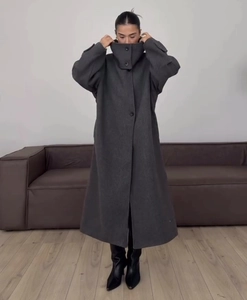 Detail of dark grey wool coat with stand collar and long oversized fit on model