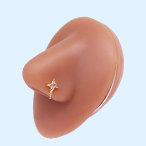 Close-up of gold nose stud with pink heart zircon on a realistic skin model