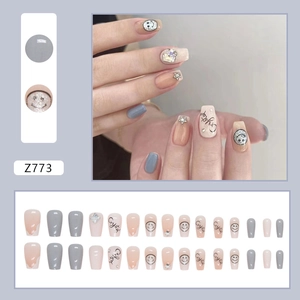 Short square false nails with glitter smiley faces and silver stars in nude and grey
