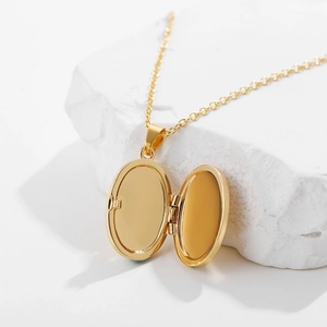 Gold stainless steel oval locket necklace with sun and moon eye design on textured stone