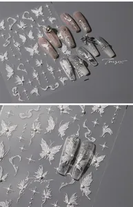 Macro detail of 3D embossed nail stickers featuring white stars, butterflies and pearls