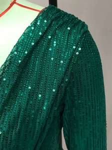 Detail shot of green sequined fabric and mesh lining on a long sleeve V-neck dress
