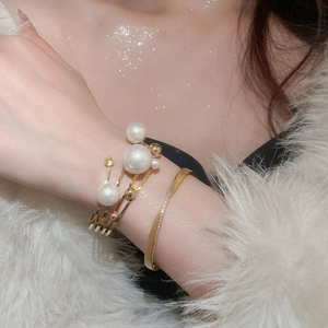 Detailed view of elegant multi-layered gold hollow bracelets with pearls on a model wrist