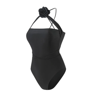 Detail of black halter bodysuit featuring a 3D floral accent and crisscross waist straps