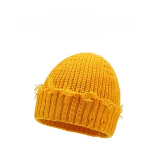 Détail du bonnet en tricot jaune gingembre avec bords effilochés et texture vintage