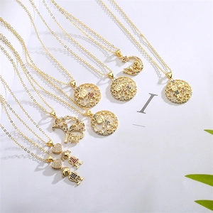 Détail de colliers dorés avec pendentifs lune, arbre et enfants en cristaux colorés