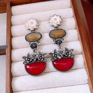 Close-up of vintage flower earrings with amber and red stones on white velvet