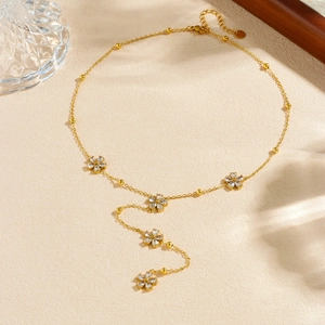 Collier en Y doré élégant avec fleurs en zircone sur un fond beige texturé sophistiqué