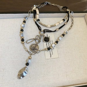 Detail of bohemian layered necklace with vintage coin pendant and marble beads