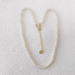 Detail of freshwater pearl necklace featuring gold lobster clasp and adjustable extension chain