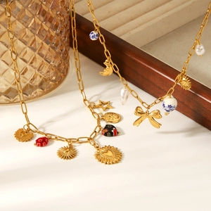 Golden paperclip chain necklaces with heart moon and star charms on a white surface
