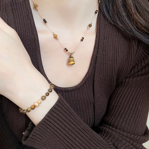 Close-up of tiger eye stone gourd pendant necklace and matching beaded bracelet on a model