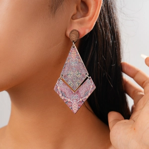 Macro detail of geometric rhombus earrings with bohemian mandala wood print pattern
