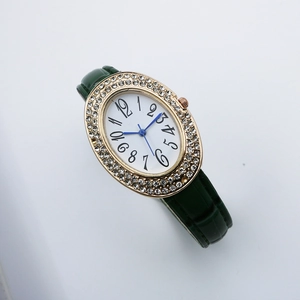 Detailed close-up of oval quartz watch with crystal bezel and green leather strap