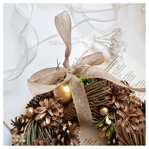 Close-up of Christmas wreath with natural pine cones, gold baubles and burlap bow