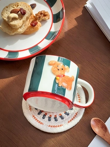 Close-up of hand-painted ceramic mug featuring embossed orange dog and green stripes