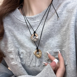 Detail of silver and gold irregular metal heart pendants on black leather cords