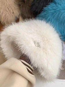 Detail of white faux fur bucket hat with metal buckle accent and thick plush texture