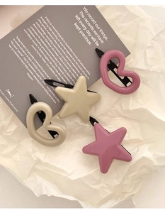 Détail des barrettes en forme d'étoile et de cœur rose et beige sur papier
