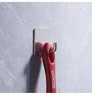 Detail of stainless steel J-shaped adhesive hook mounted on grey marble wall