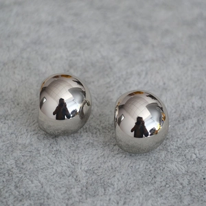 Macro shot of silver sphere earrings with polished surface on soft grey fabric