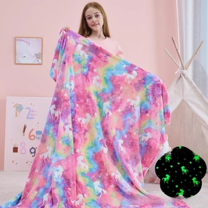 Detail showing glowing unicorn and star patterns on pink flannel blanket in the dark
