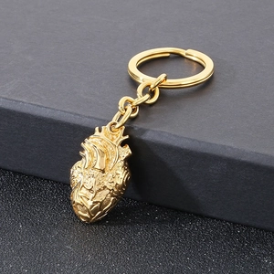 Macro shot of a golden anatomical heart keychain with detailed gothic metal texture