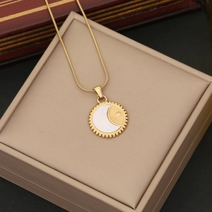 Close-up of gold moon and sun pendant with white inlay on beige leather surface