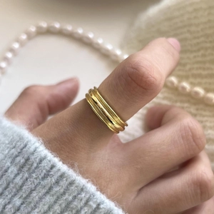Close-up of triple-layered gold minimalist ring worn with soft pearl necklace details