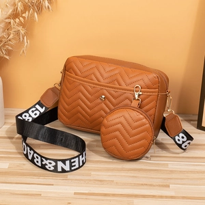 Detail of brown V-quilted PU leather crossbody bag with lettered strap and round pouch