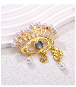 Detailed shot of Evil Eye brooch with pearls, sunburst charms and golden metal finish