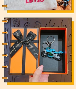 Blue motorcycle keychain model held in hand with a premium orange gift box and ribbon