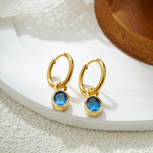 Close-up of 18K gold hoop earrings featuring removable oval blue zircon pendants