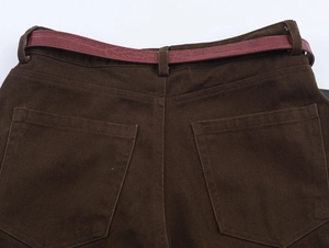 Dettaglio dei pantaloni in twill testa di moro con cintura rossa effetto coccodrillo