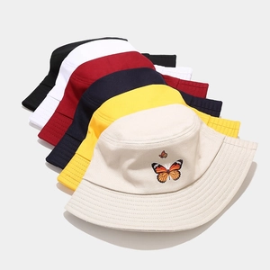 Plusieurs couleurs de bobs en coton avec papillon brodé sur le modèle beige