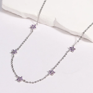 Detail of silver chain necklace featuring purple flower charms with sparkling crystals