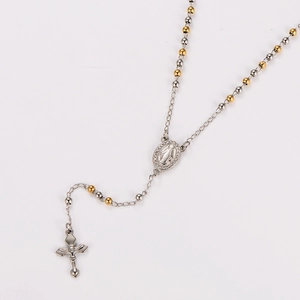 Macro detail of two-tone beaded necklace featuring a rhinestone medal and crucifix