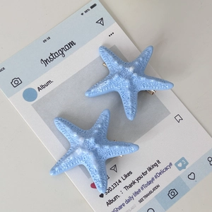 Detail of light blue starfish hair clips with realistic texture and metal duckbill grip
