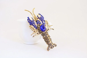 Macro shot of blue rhinestone lobster keychain with vintage gold metal details