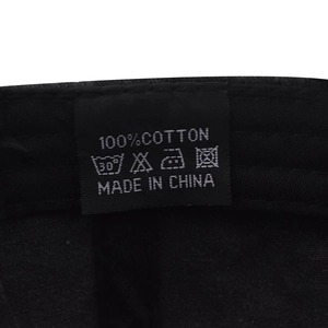 Close-up of 100% cotton fabric and washing instruction label on black baseball cap