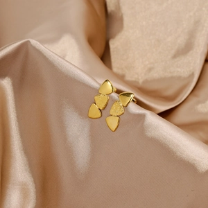 Detail of gold stacked triangle earrings with lava texture on champagne silk fabric
