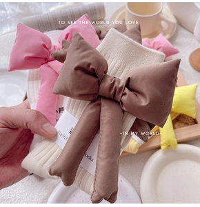 Detailed view of ribbed knit socks featuring a detachable 3D stuffed oversized bow accent