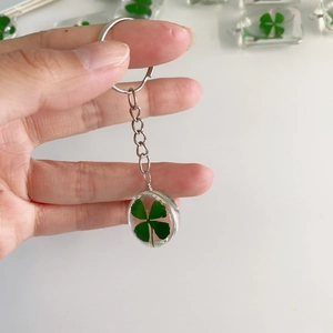 Macro shot of a clear sphere keychain featuring a real green four-leaf clover specimen inside
