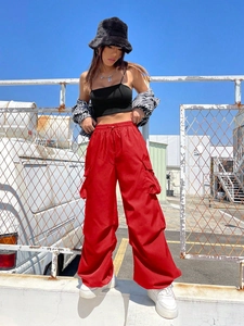 Street style shot of red multi-pocket cargo pants paired with black crop top and fuzzy hat